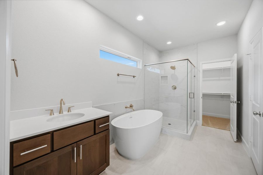 Indulge in a spa-like experience with a freestanding tub, step-in shower, dual sinks, a private water closet, and ample storage.