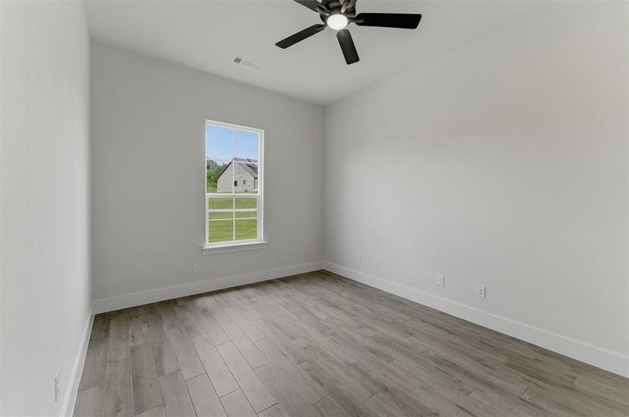 Interior space featuring wood-finish flooring, white baseboards, a white window frame, and a ceiling fan with integrated lighting