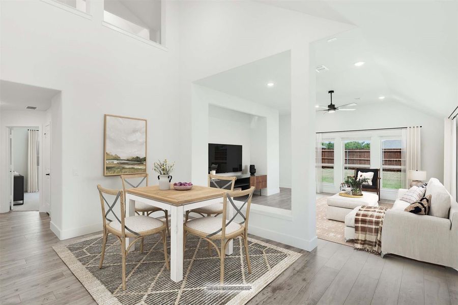 Open-concept dining area with white table and wood chairs, flowing into living room with high ceilings and hardwood floors Open-concept dining area with white table and wood chairs, flowing into living room with high ceilings and hardwood floors