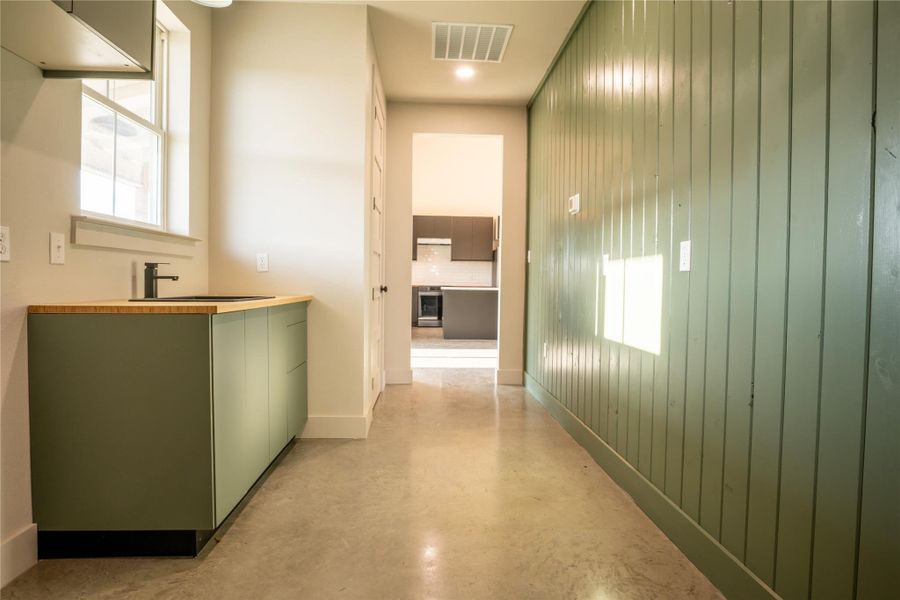 Hallway featuring plenty of natural light, finished concrete flooring, and wood walls