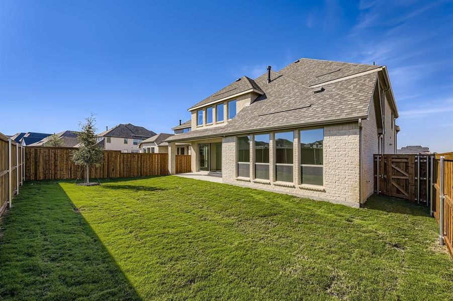 Back of property featuring brick siding, a patio, roof with shingles, and a fenced backyard