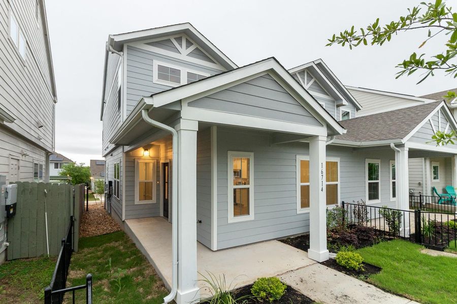 The property features a light gray exterior with white trim, a covered porch, and a well-maintained front yard with landscaping