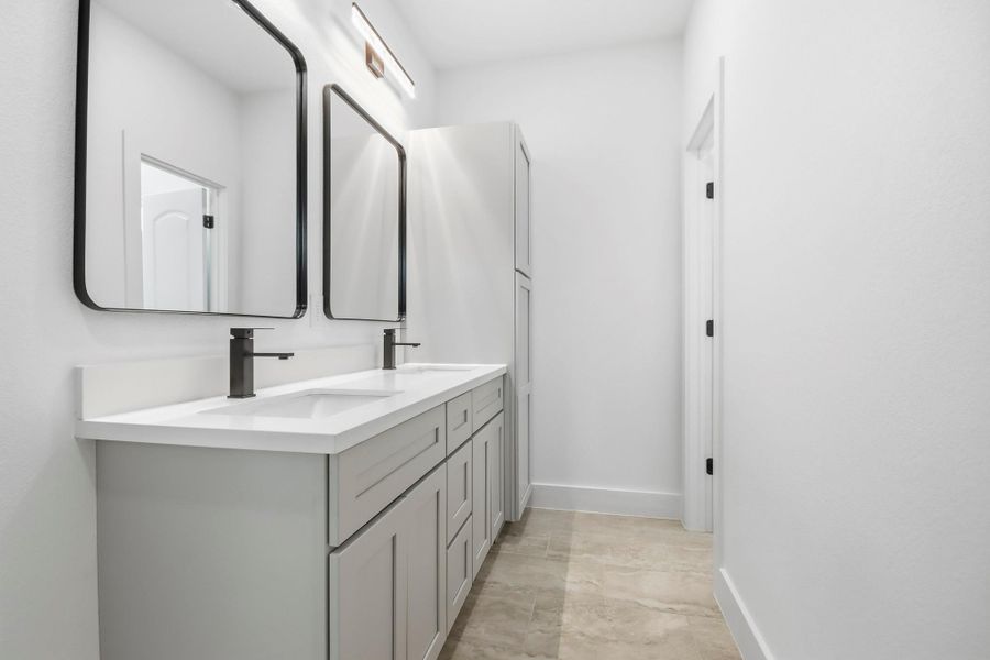 Sleek and modern bathroom featuring a double vanity with stylish black fixtures, ample storage, and elegant flooring.