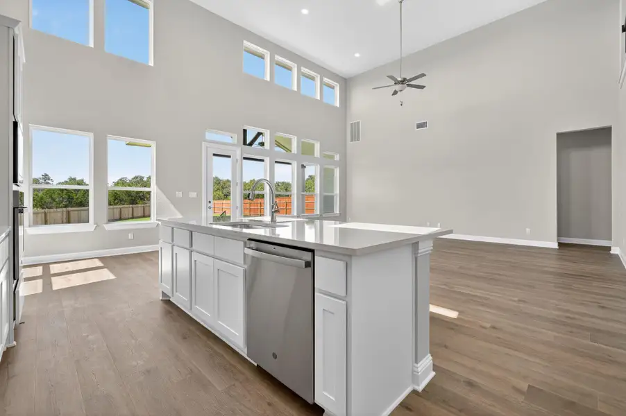 Kitchen with white cabinetry, stainless steel dishwasher, open floor plan, dark wood-style floors, and an island with sink