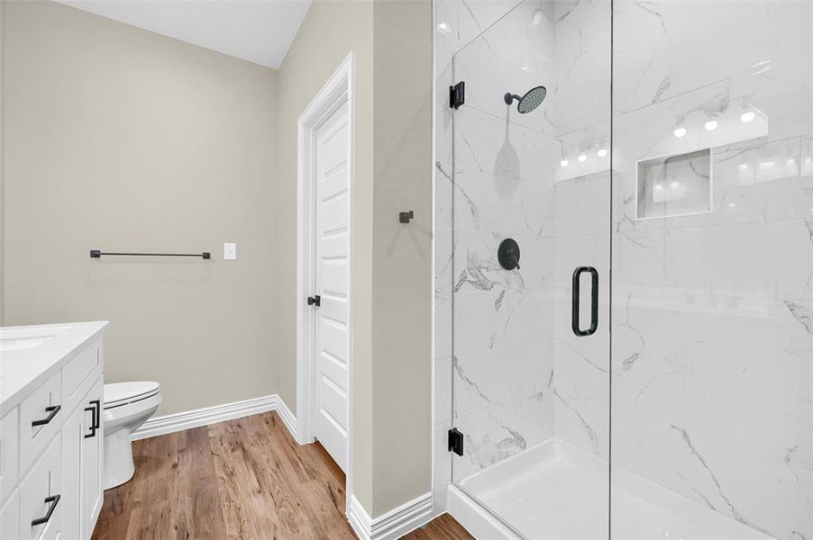 Bathroom featuring walk in shower, toilet, vanity, and hardwood / wood-style flooring