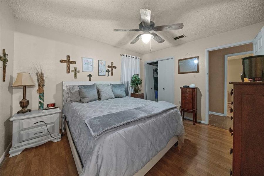 Bedroom featuring a closet, a textured ceiling, wood finished floors, and a ceiling fan