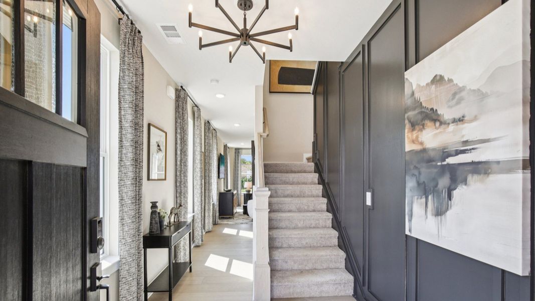 Entry with accent wall, hallway to living room, and staircase