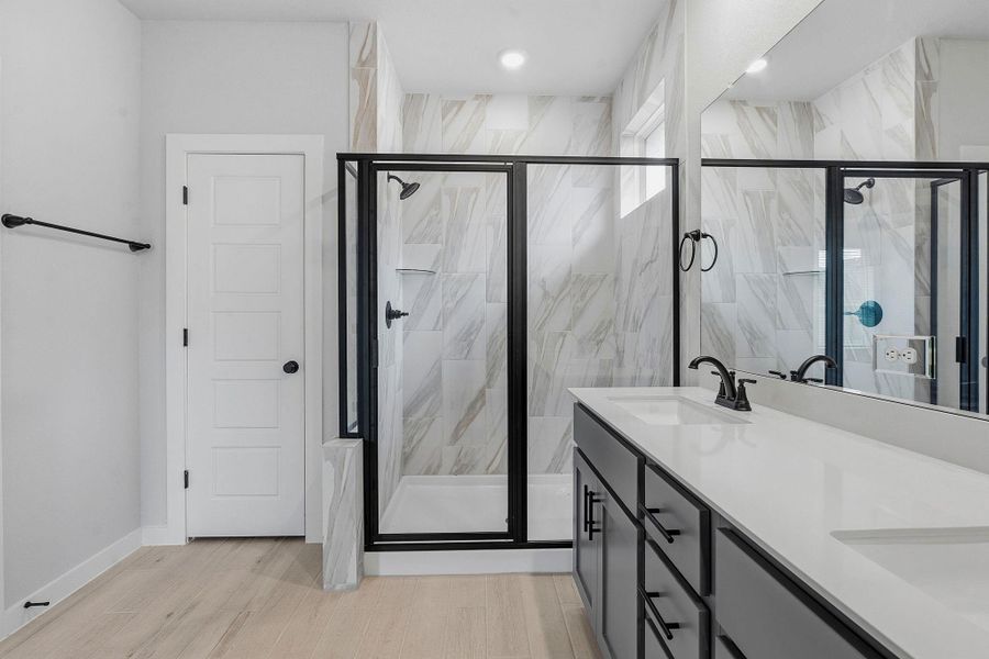 Modern primary bathroom featuring dual sinks, a spacious walk-in shower, and ample vanity space.