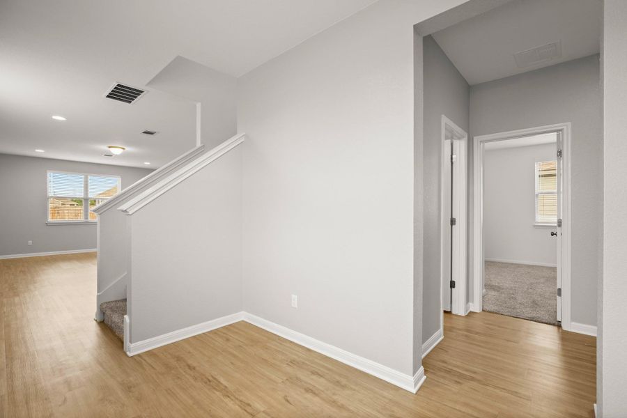 Hall featuring light wood finished floors, stairway, and recessed lighting