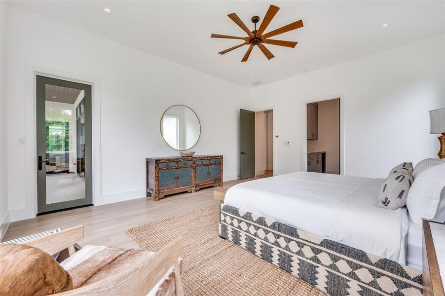 Bedroom with ensuite bathroom, access to outside, light wood-type flooring, and ceiling fan