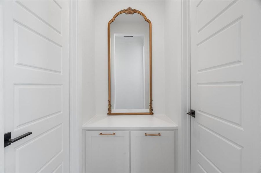 Built in laundry hampers between entrance to separate primary closets Built in laundry hampers between entrance to separate primary closets