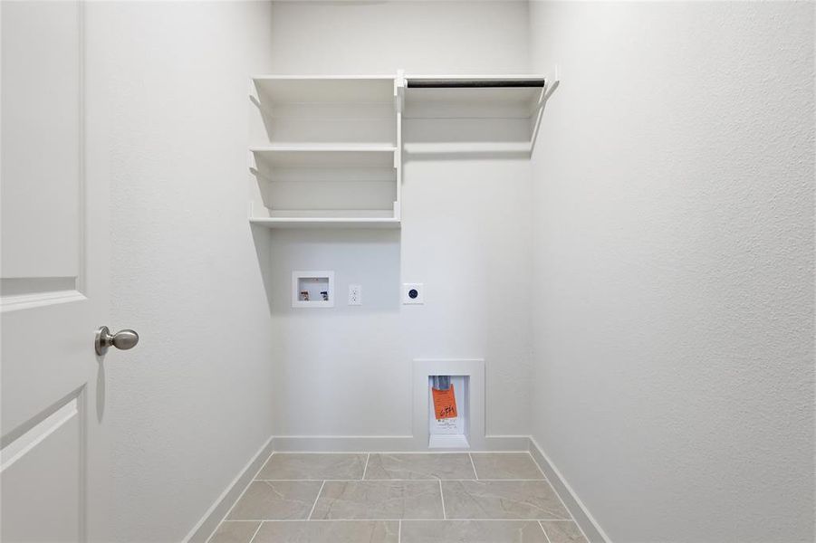 Dedicated laundry area featuring built-in shelving, a hanging rod, tile flooring, and utility hookups Dedicated laundry area featuring built-in shelving, a hanging rod, tile flooring, and utility hookups