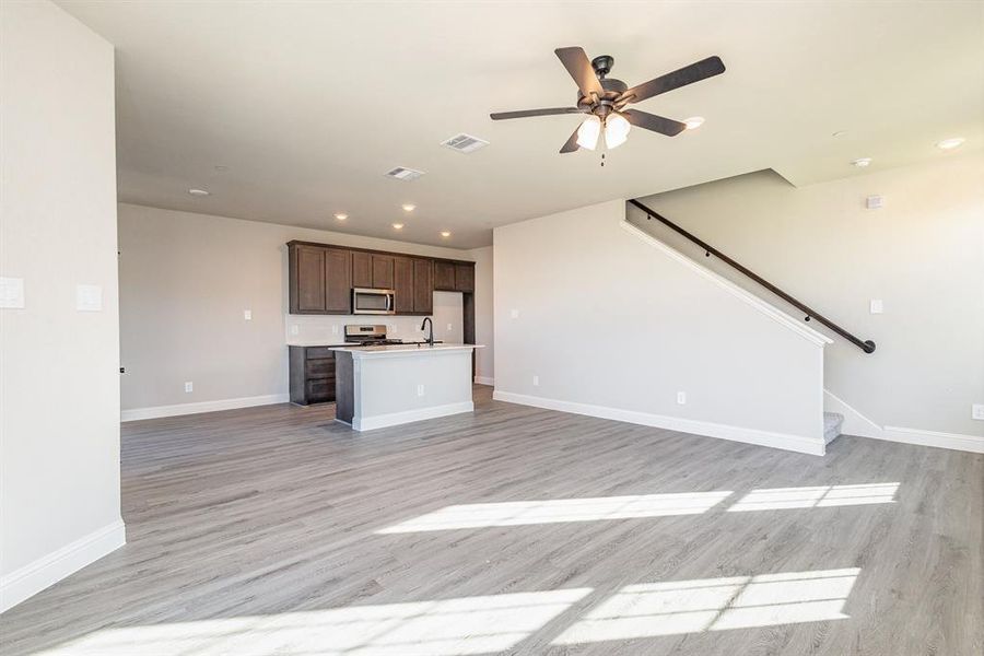 Unfurnished living room featuring sink, light wood-type flooring, and ceiling fan