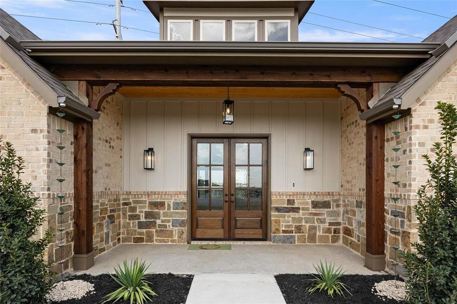 Doorway to property with french doors, stone siding, and covered porch Doorway to property with french doors, stone siding, and covered porch