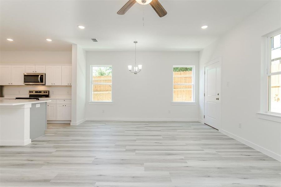 Kitchen featuring electric stove, light hardwood / wood-style flooring, a wealth of natural light, and white cabinetry