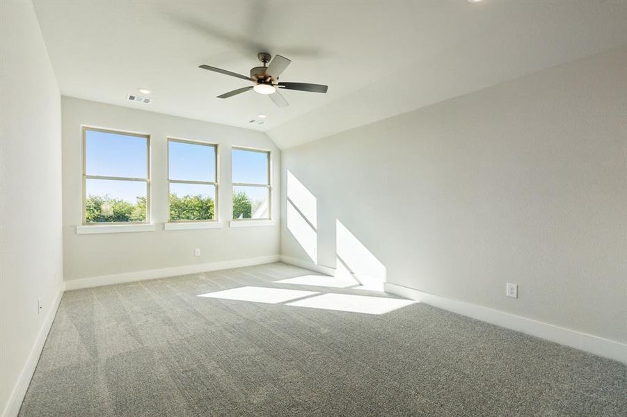 Empty room featuring light carpet, lofted ceiling, and ceiling fan