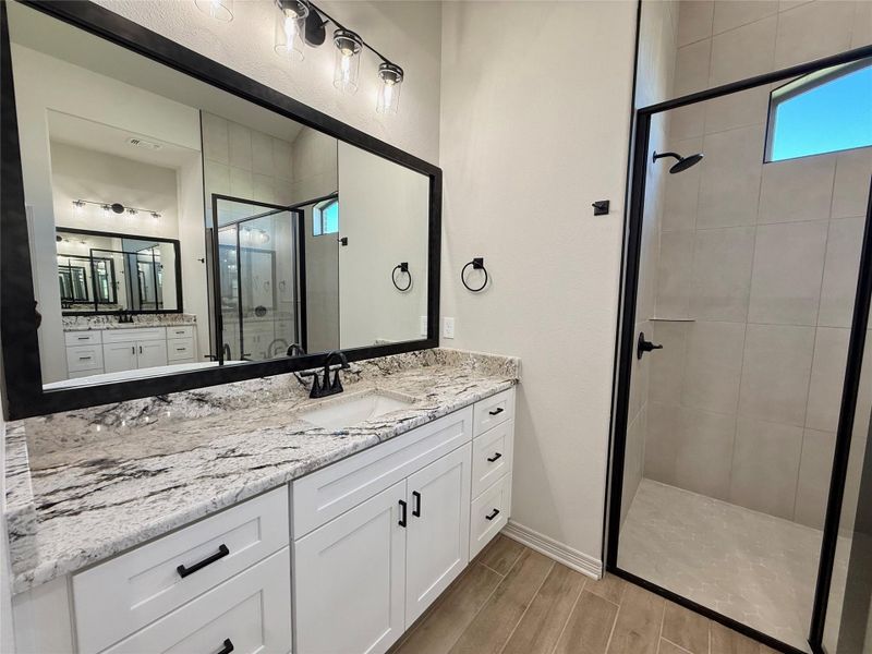Bathroom with a stall shower, vanity, and wood tiled floors