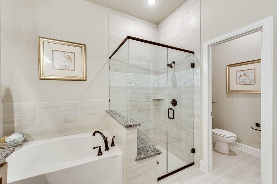 Master bathroom with soaking tub, glass-enclosed tile shower, and separate water closet