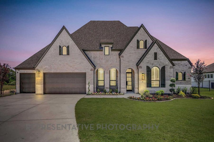 French country inspired facade with brick siding, a shingled roof, and driveway French country inspired facade with brick siding, a shingled roof, and driveway