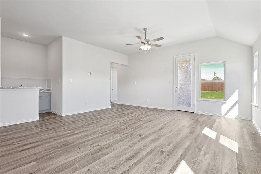 Unfurnished living room with lofted ceiling, ceiling fan, and light hardwood / wood-style flooring