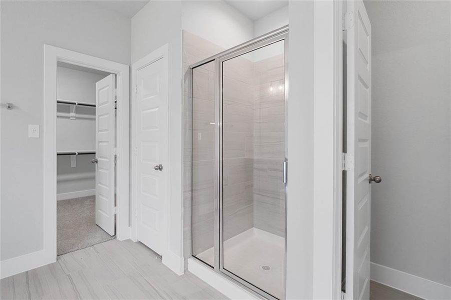 This primary bathroom is definitely move-in ready! Featuring a framed walk-in shower with tile surround, separate garden tub for soaking after a long day with custom tile detailing, stained cabinets with light countertops, spacious walk-in closet with shelving, high ceilings, custom paint, sleek and modern finishes.