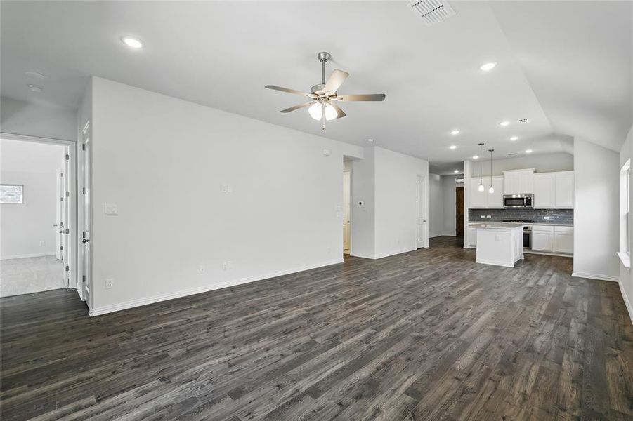 Unfurnished living room with dark wood-style floors, ceiling fan, visible vents, and recessed lighting