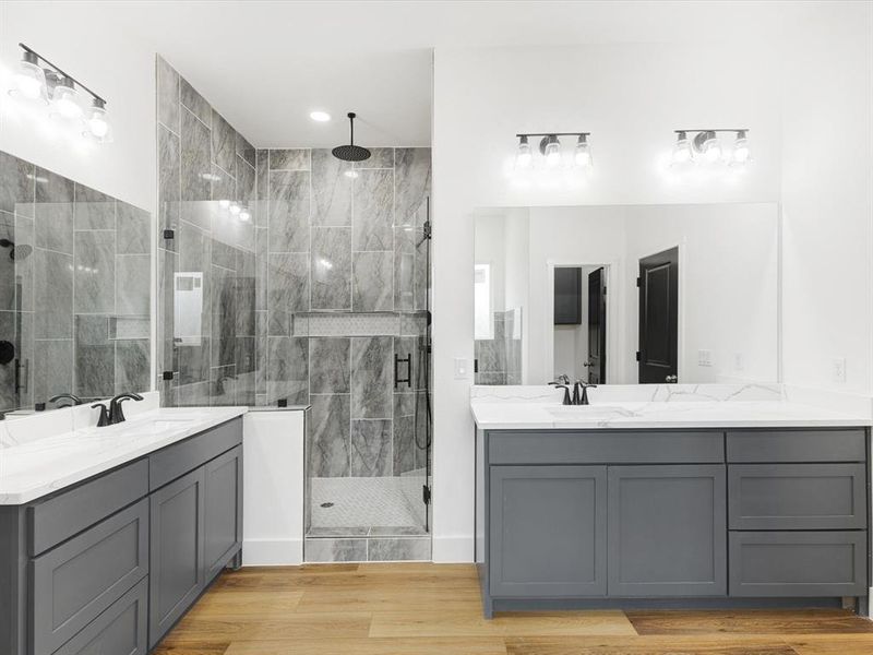Full bath featuring two vanities, light wood-style floors, and a stall shower Full bath featuring two vanities, light wood-style floors, and a stall shower