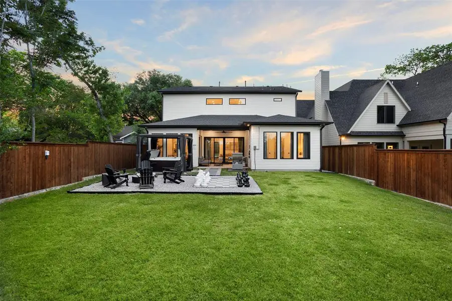 Expansive backyard featuring a manicured lawn, a gravel patio area, and a privacy fence