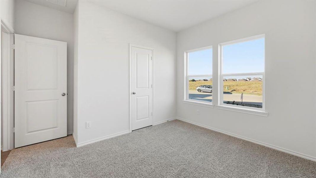 Unfurnished bedroom with light colored carpet and baseboards