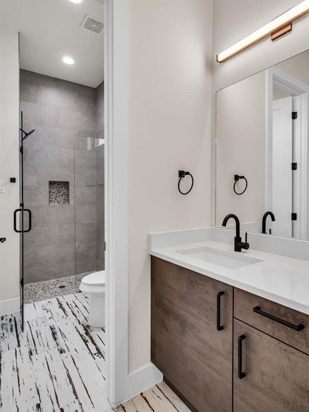 Bathroom with vanity, walk in shower, and toilet