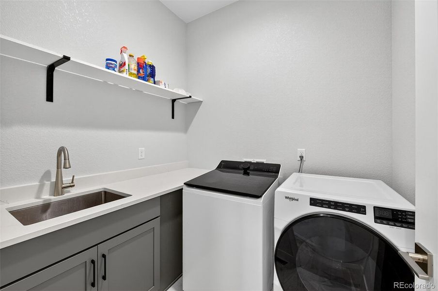 Laundry Room – Convenient laundry area with upper shelving, utility sink, and extended counter space for folding and organization.