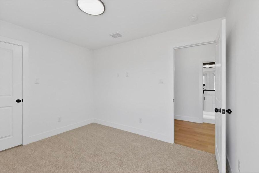 Unfurnished bedroom featuring light carpet and baseboards