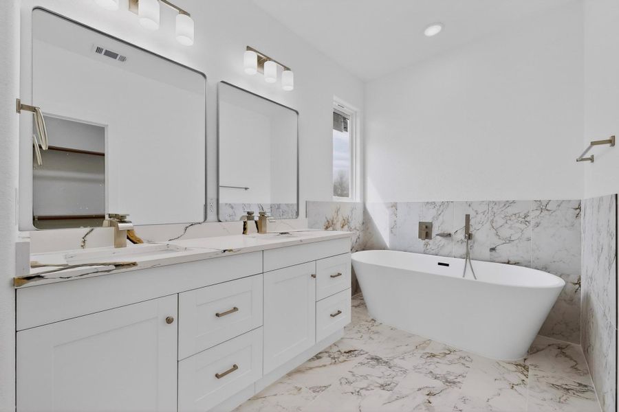 Bathroom with double vanity, tile walls, a freestanding tub