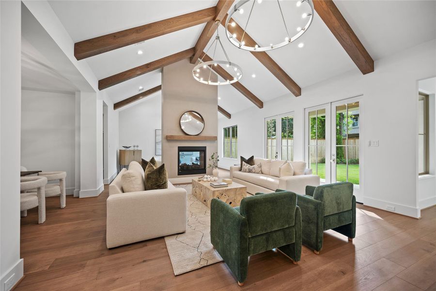 This spacious living area features vaulted ceilings with wooden beams, a modern fireplace, and French doors that open to a backyard. Perfect for cozy and bright living. This spacious living area features vaulted ceilings with wooden beams, a modern fireplace, and French doors that open to a backyard. Perfect for cozy and bright living.