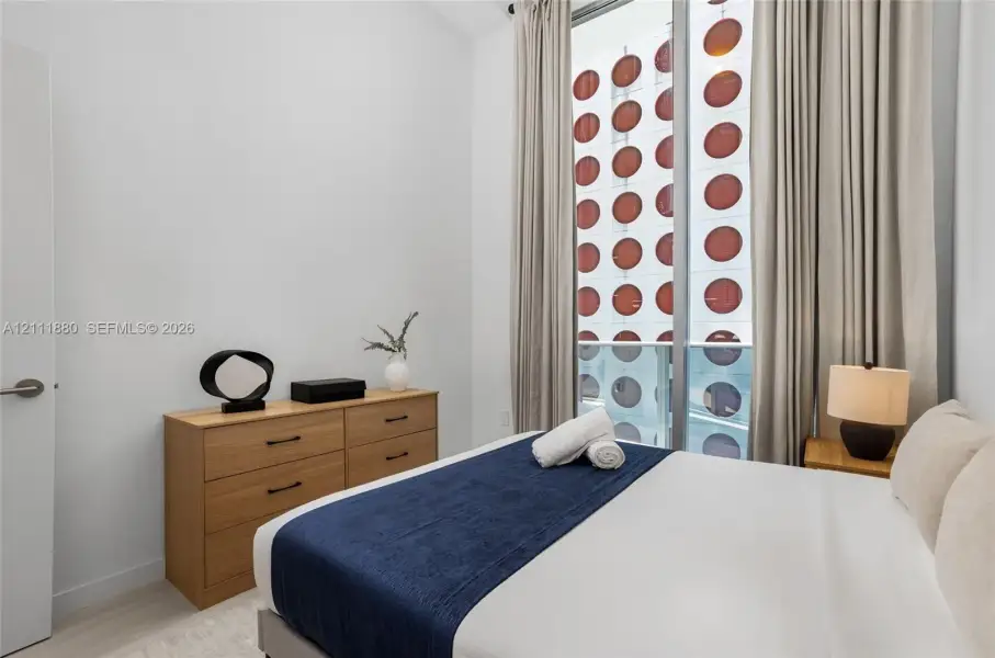 Floor-to-ceiling windows with integrated exterior decorative screening, high ceilings, and light-tone wood-finish flooring
