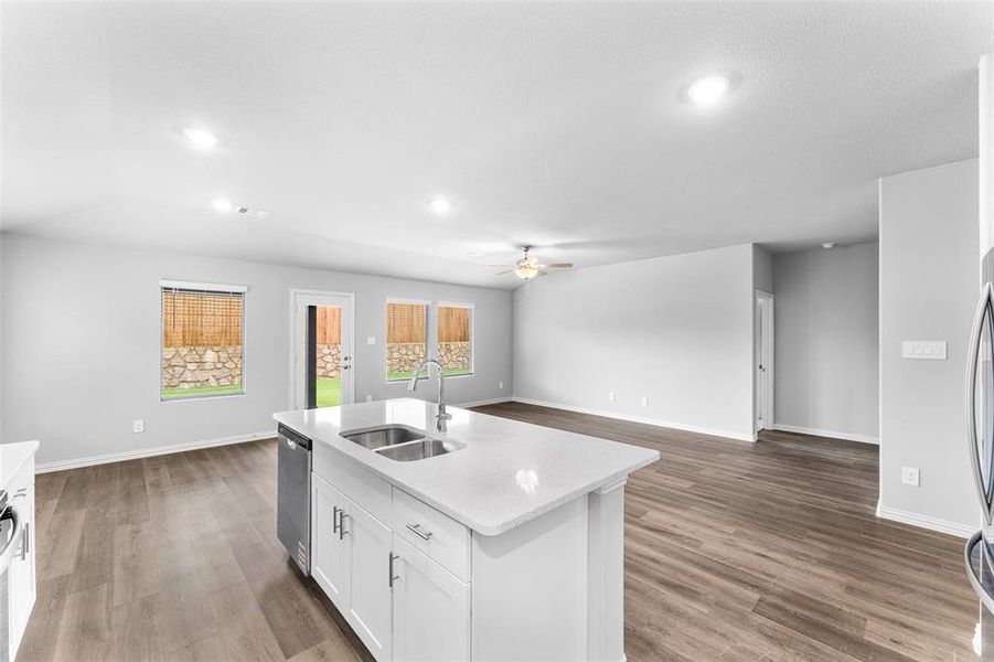 Kitchen featuring dishwasher, a ceiling fan, white cabinets, a center island with sink, and open floor plan Kitchen featuring dishwasher, a ceiling fan, white cabinets, a center island with sink, and open floor plan