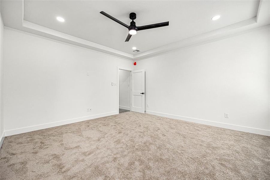 Primary Bedroom-This spacious, carpeted room features a modern ceiling fan, recessed lighting, and a minimalist design with white walls, offering a blank canvas for personalization.