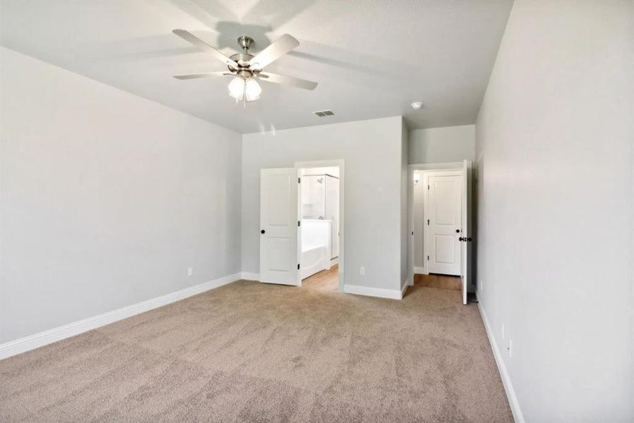 Unfurnished bedroom with light carpet, ceiling fan, and ensuite bath