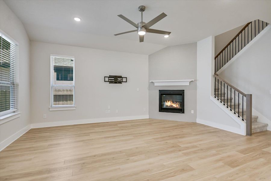 Hardwood floors and a corner fireplace anchor this light-filled living area next to the stairs. Hardwood floors and a corner fireplace anchor this light-filled living area next to the stairs.