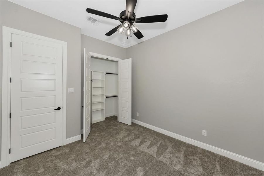 Unfurnished bedroom featuring carpet flooring, a closet, and a ceiling fan