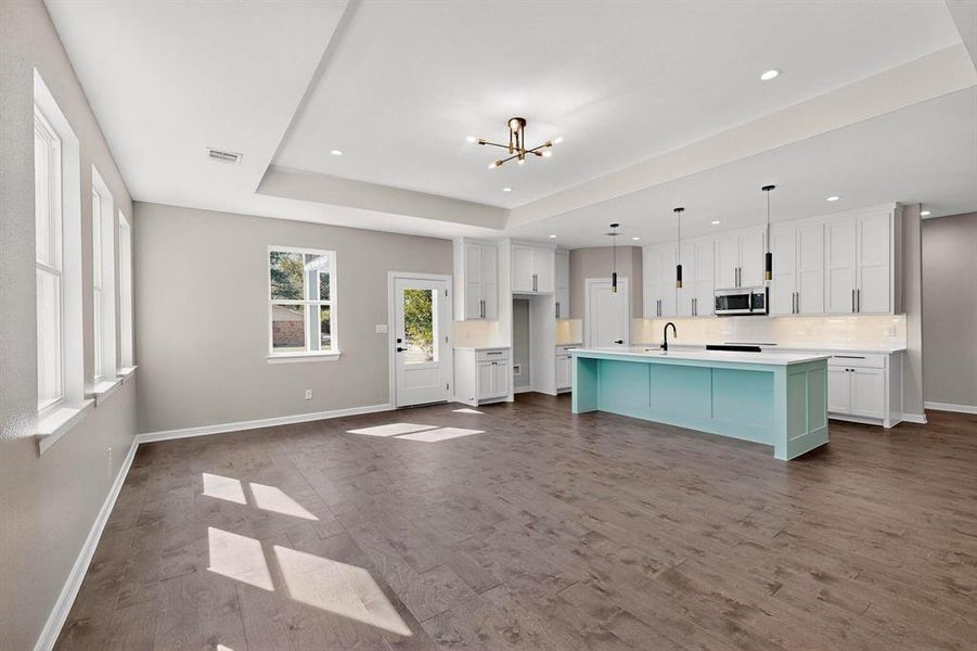 Kitchen with white cabinetry, a center island with sink, decorative backsplash, light countertops, and recessed lighting Kitchen with white cabinetry, a center island with sink, decorative backsplash, light countertops, and recessed lighting