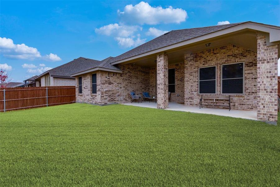 Rear view of property featuring a lawn and a patio area