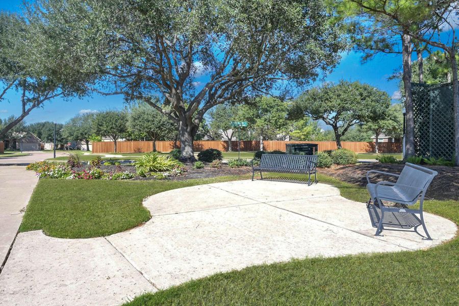 The neighborhood has manicured landscaping and park benches throughout.