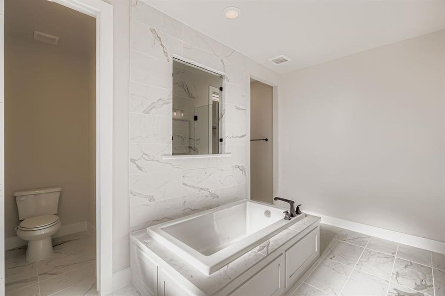 Bathroom with light marble finish flooring and a garden tub