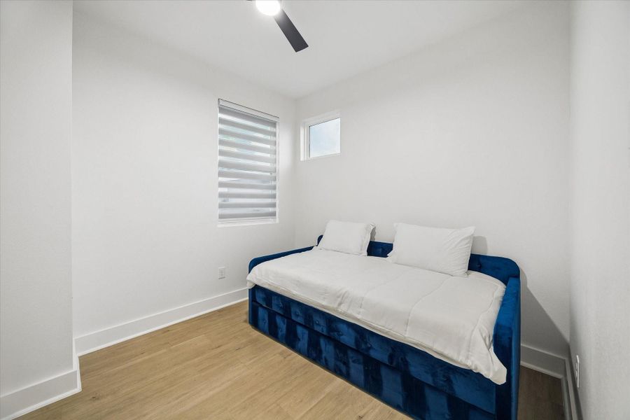 Versatile first-floor flex room shown as a guest space, featuring wood-look flooring, a ceiling fan, and natural light. The room can also serve as a private home office or additional sitting area. Versatile first-floor flex room shown as a guest space, featuring wood-look flooring, a ceiling fan, and natural light. The room can also serve as a private home office or additional sitting area.