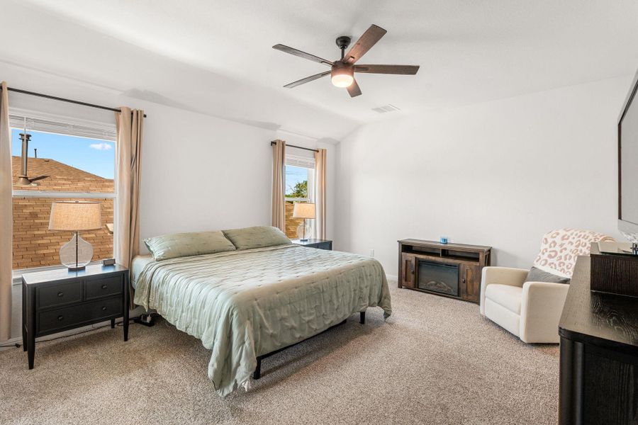 A well-lit primary bedroom offers comfortable carpet flooring and ample space for relaxation. A well-lit primary bedroom offers comfortable carpet flooring and ample space for relaxation.