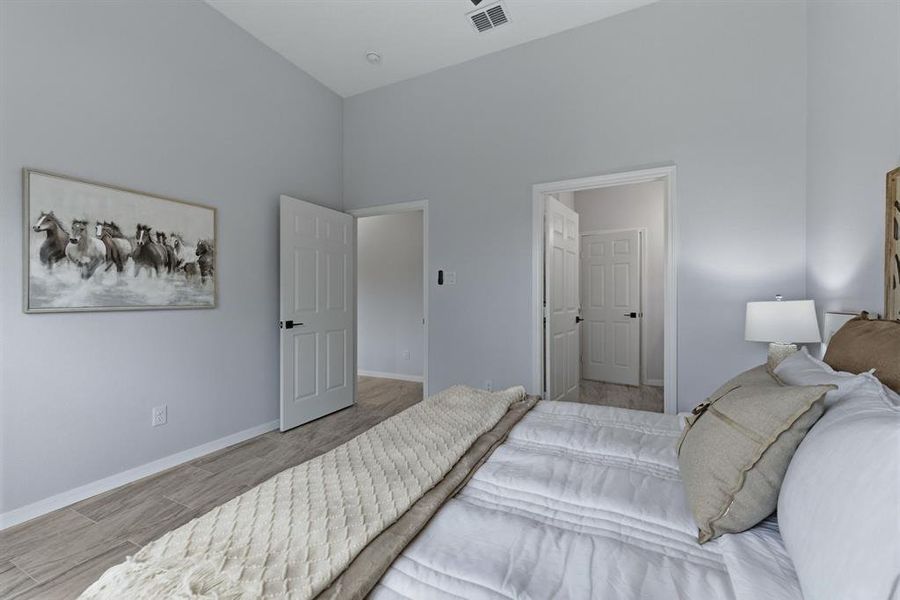 Bedroom featuring light wood-style floors and a high ceiling Bedroom featuring light wood-style floors and a high ceiling