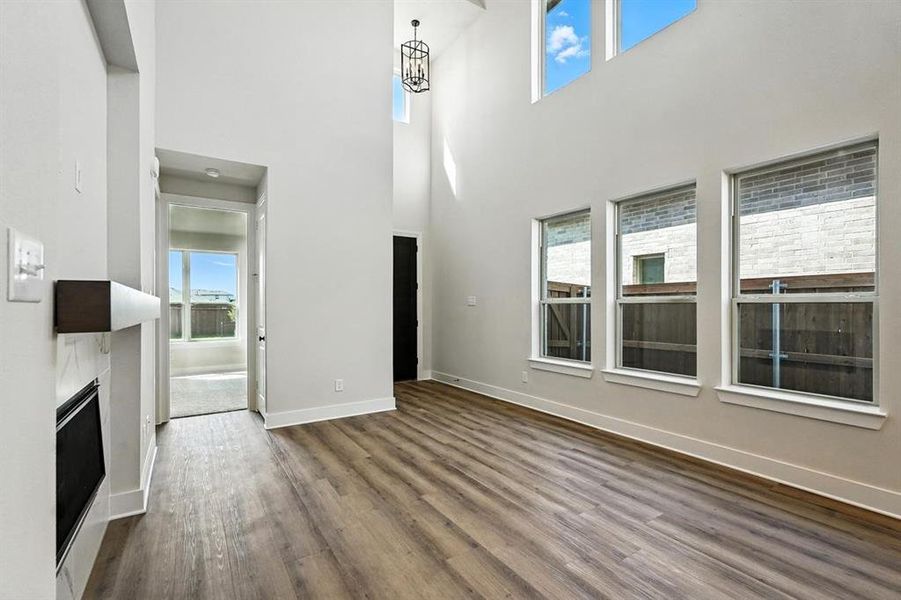 Unfurnished living room with dark wood-style flooring, a high end fireplace, and a high ceiling Unfurnished living room with dark wood-style flooring, a high end fireplace, and a high ceiling