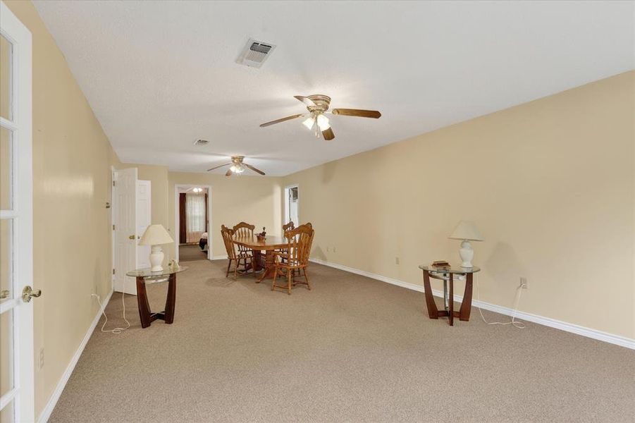 Spacious living area featuring neutral carpet flooring and light-toned walls and ceiling fans