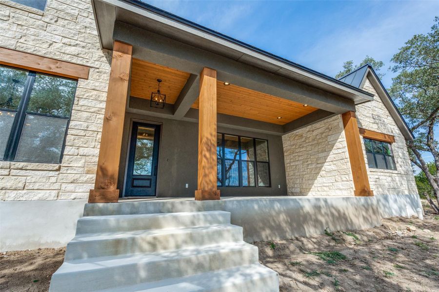 View of exterior entry with stone siding and a porch